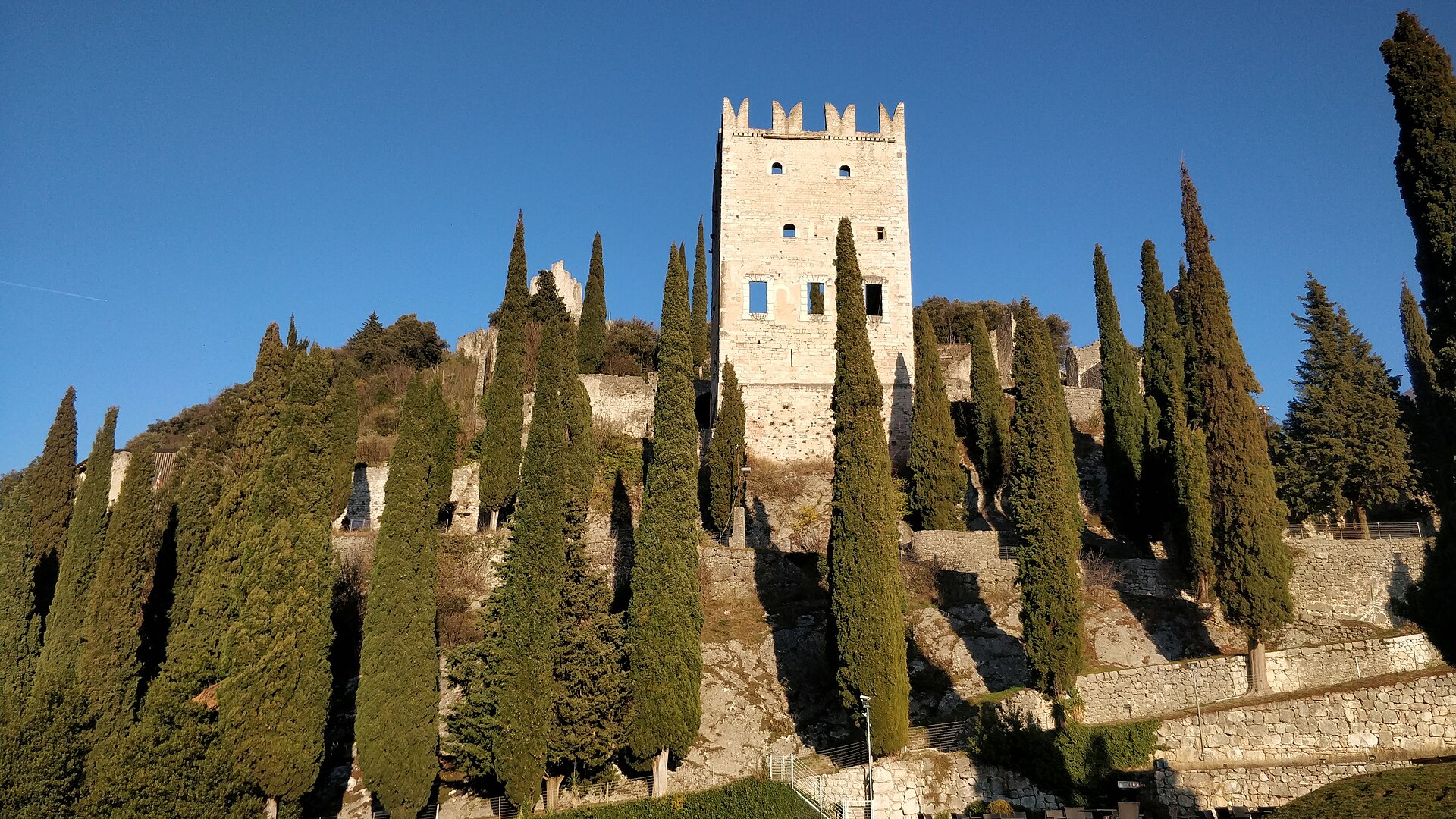 Stone tower and cypress trees at Arco Castle