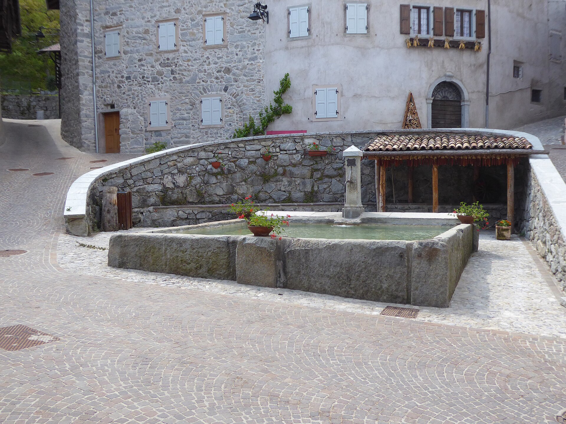 Historic stone fountain and rural houses in the village of Rango