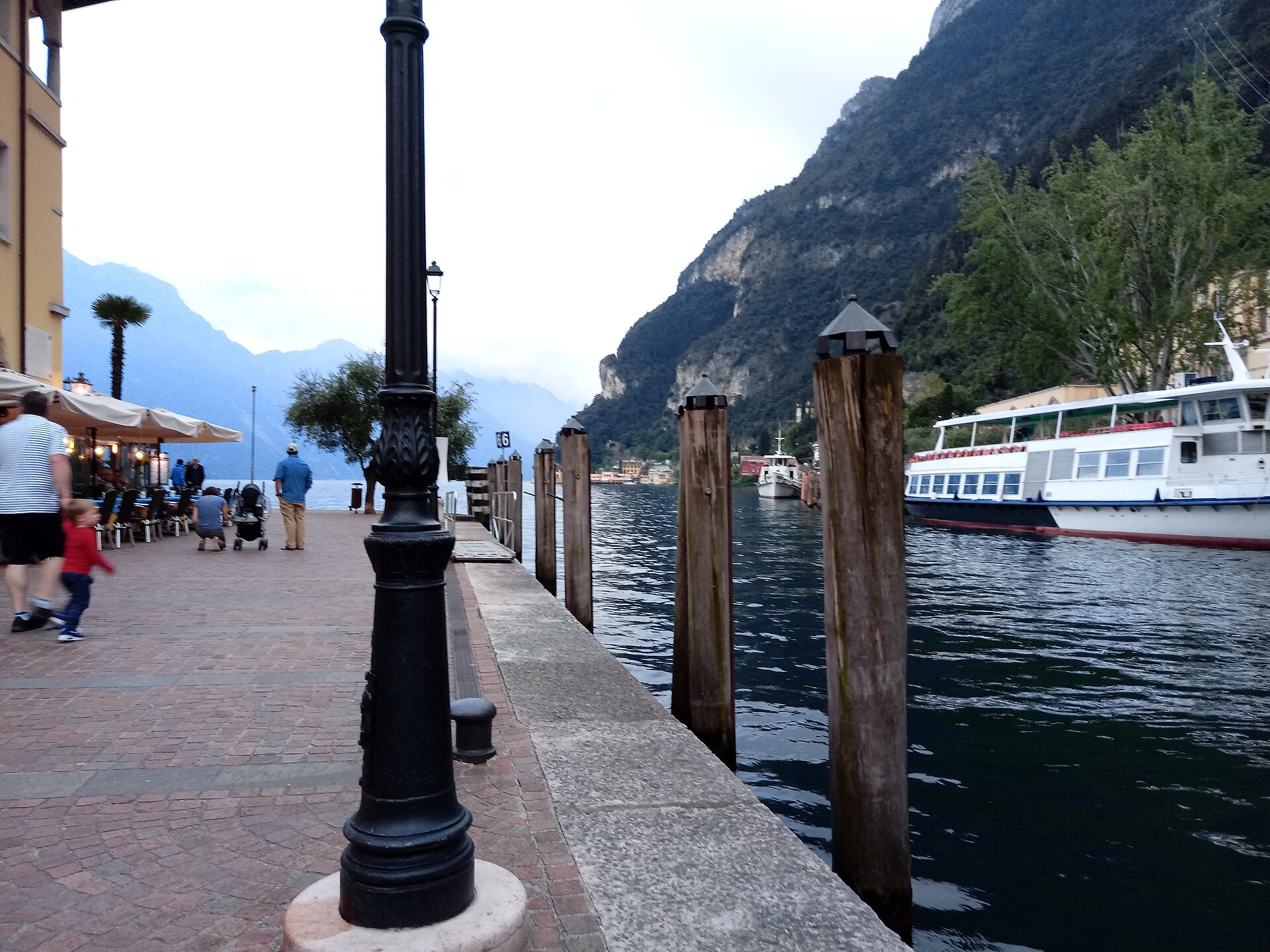 Promenade, boats and mountains at the old harbour of Riva del Garda